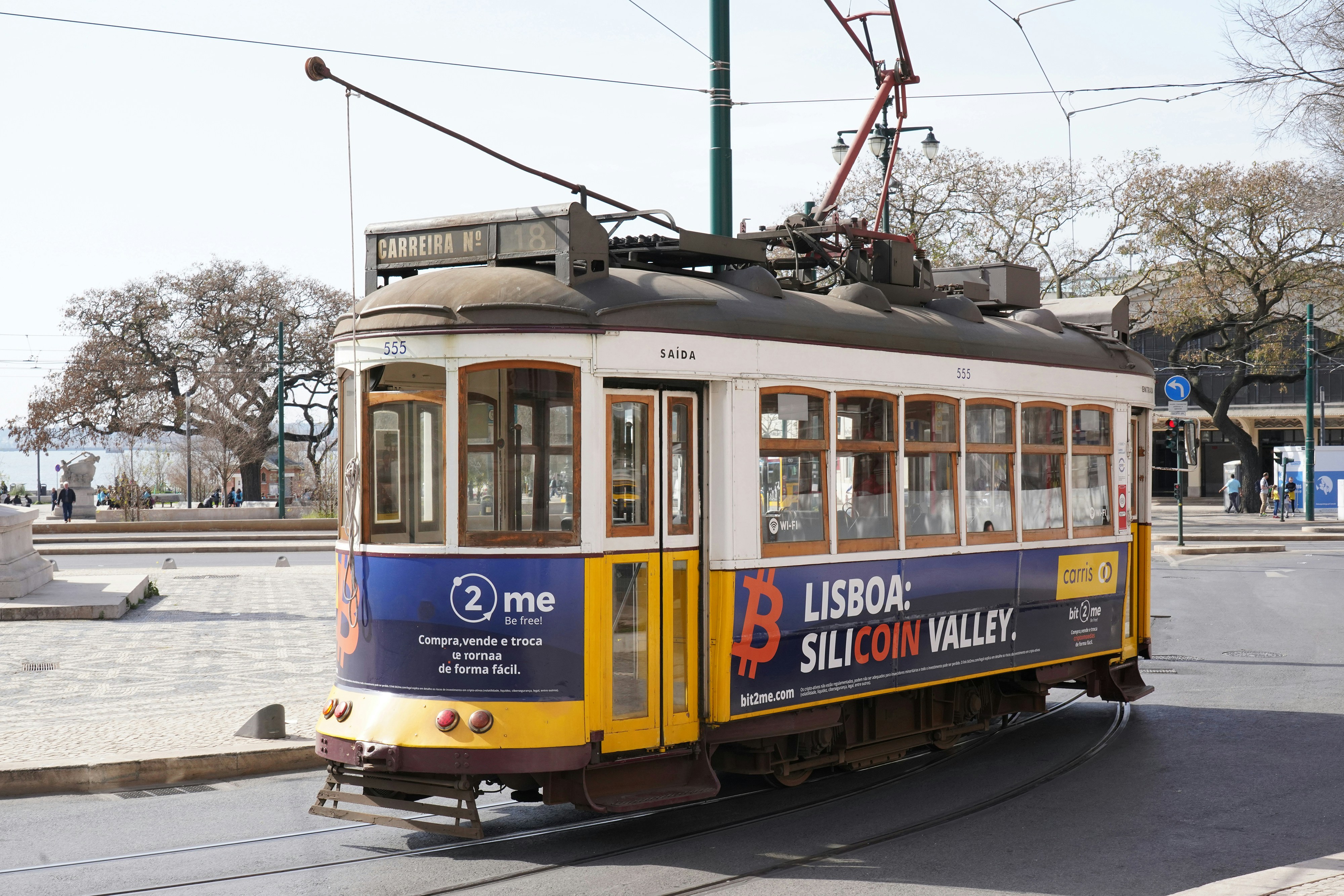A yellow tram runs on the city streets.