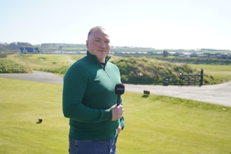 Man holding microphone on golf course.