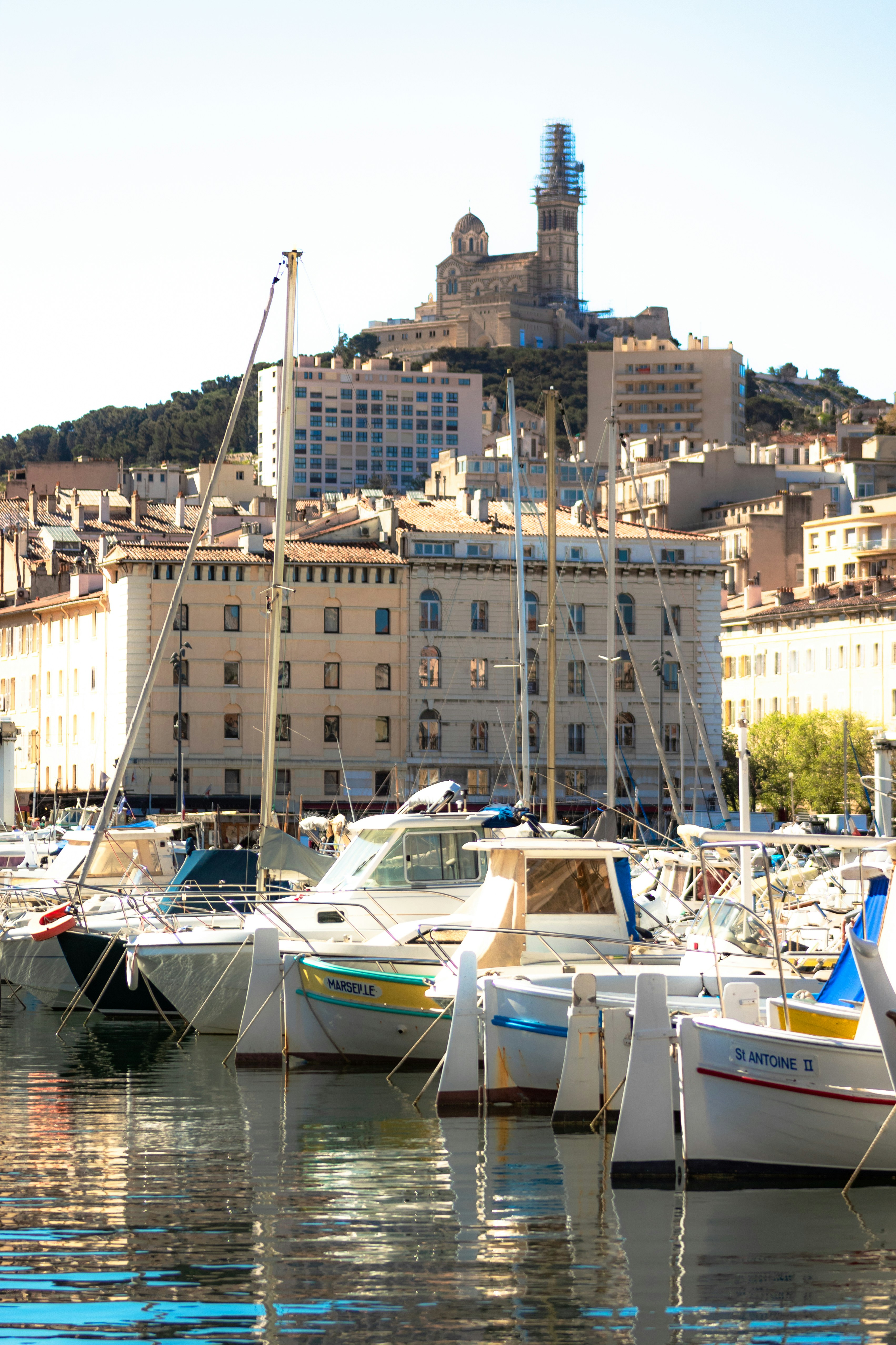 Boats docked in a harbor with a hilltop structure.