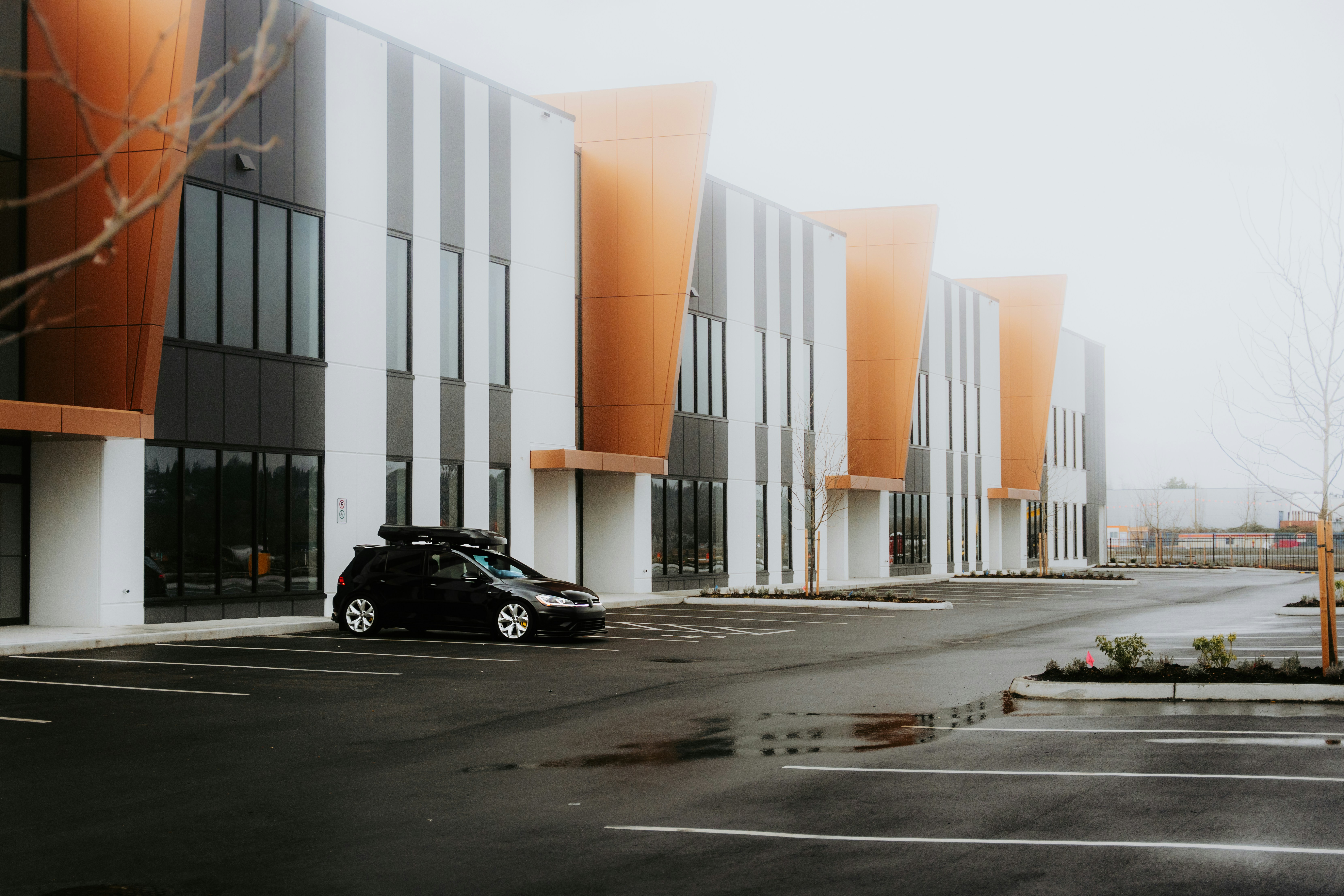 A black car parks near a modern building.