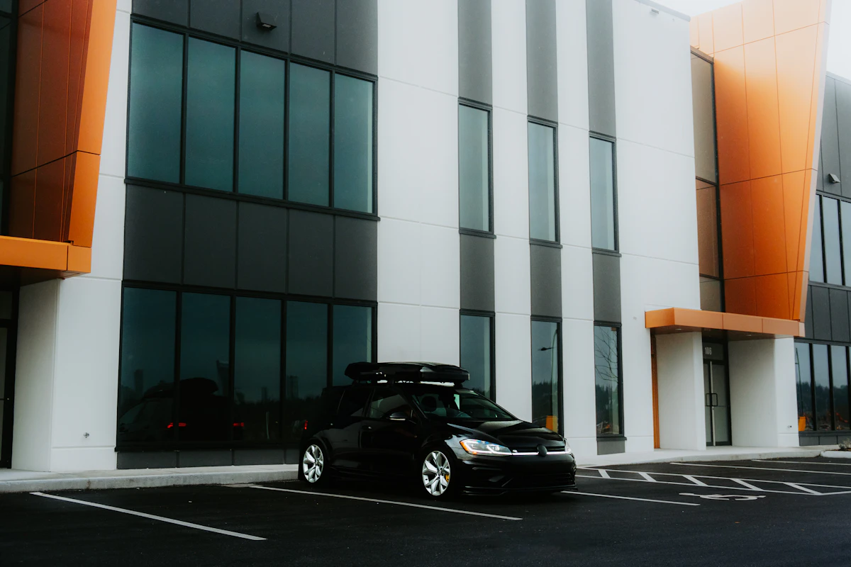 A black car parked in front of a modern building