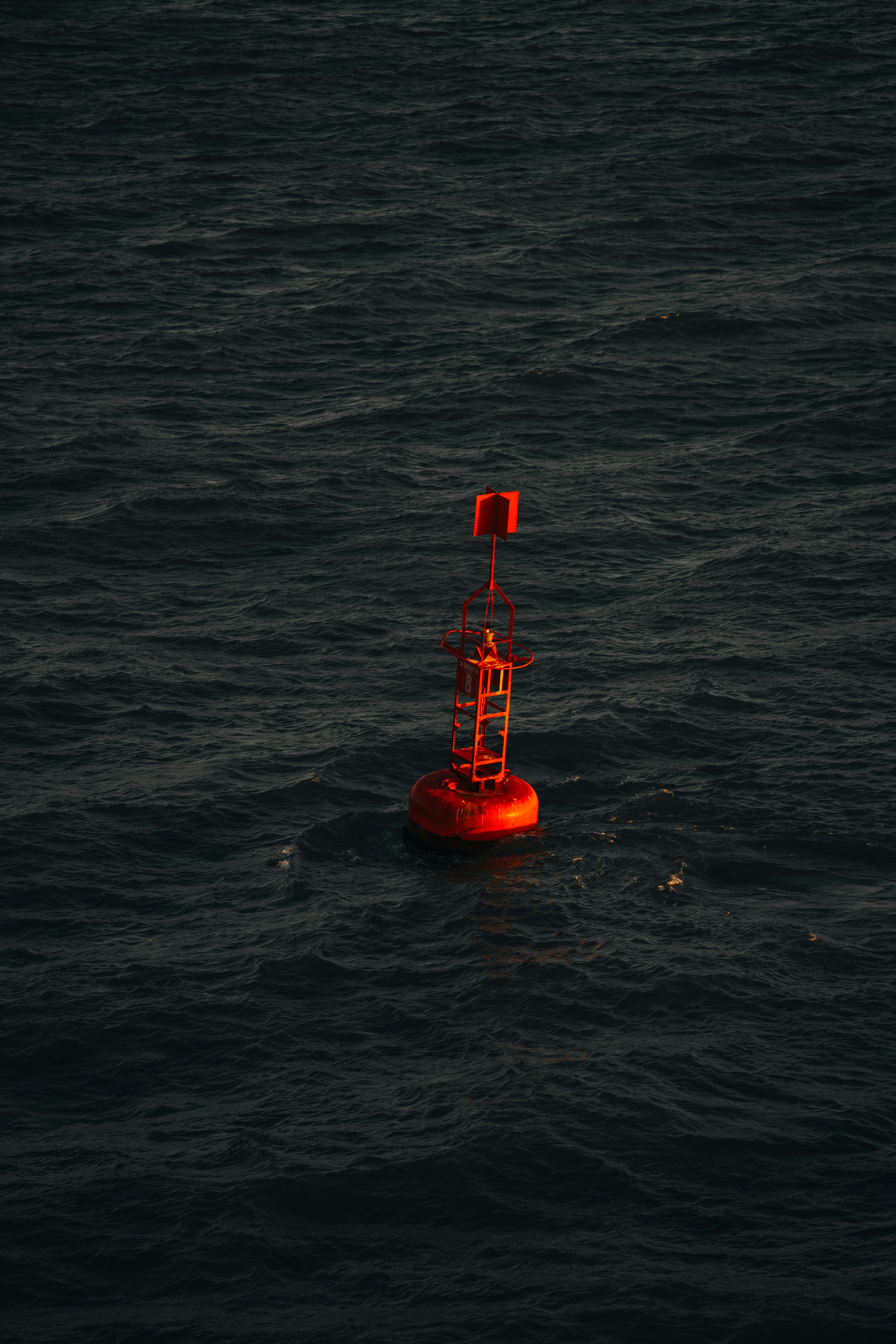 Red buoy floats on dark, choppy water.