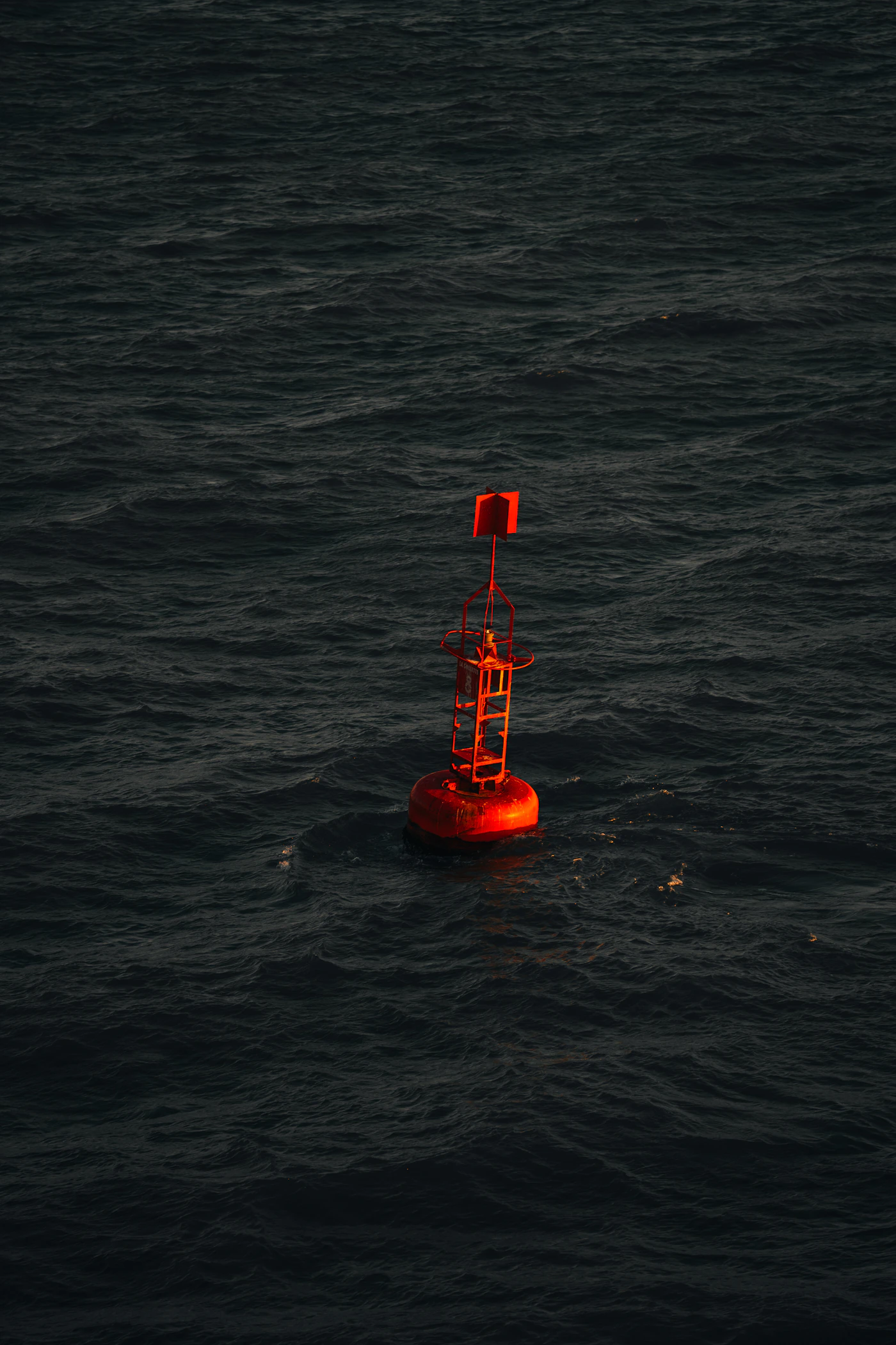 Red navigation buoy floating on dark, choppy water, representing the practical steps to find out which maritime injury system applies