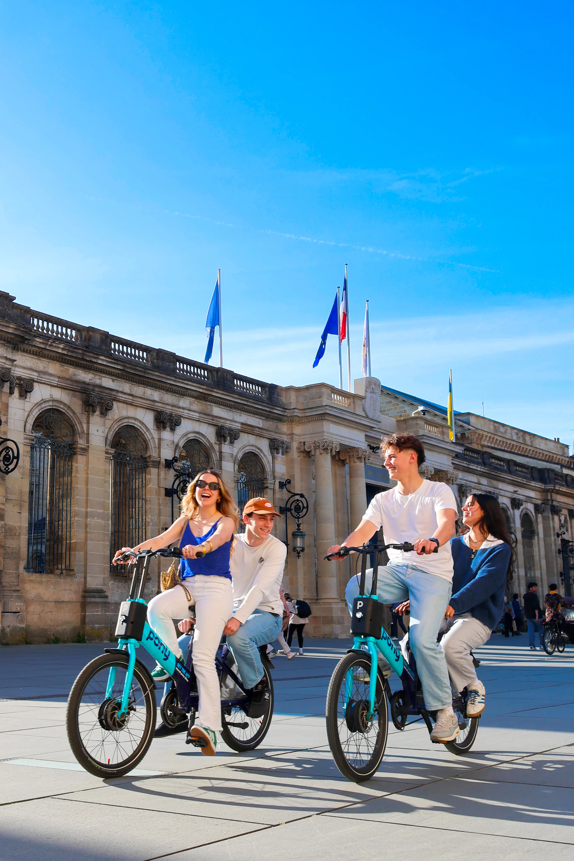 Friends ride bikes in front of a historic building.