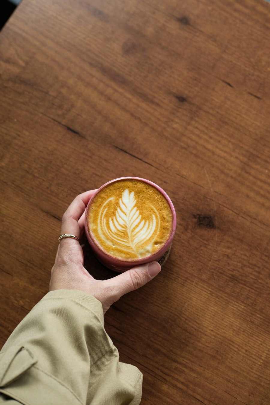 Latte con arte en espuma sostenido con la mano