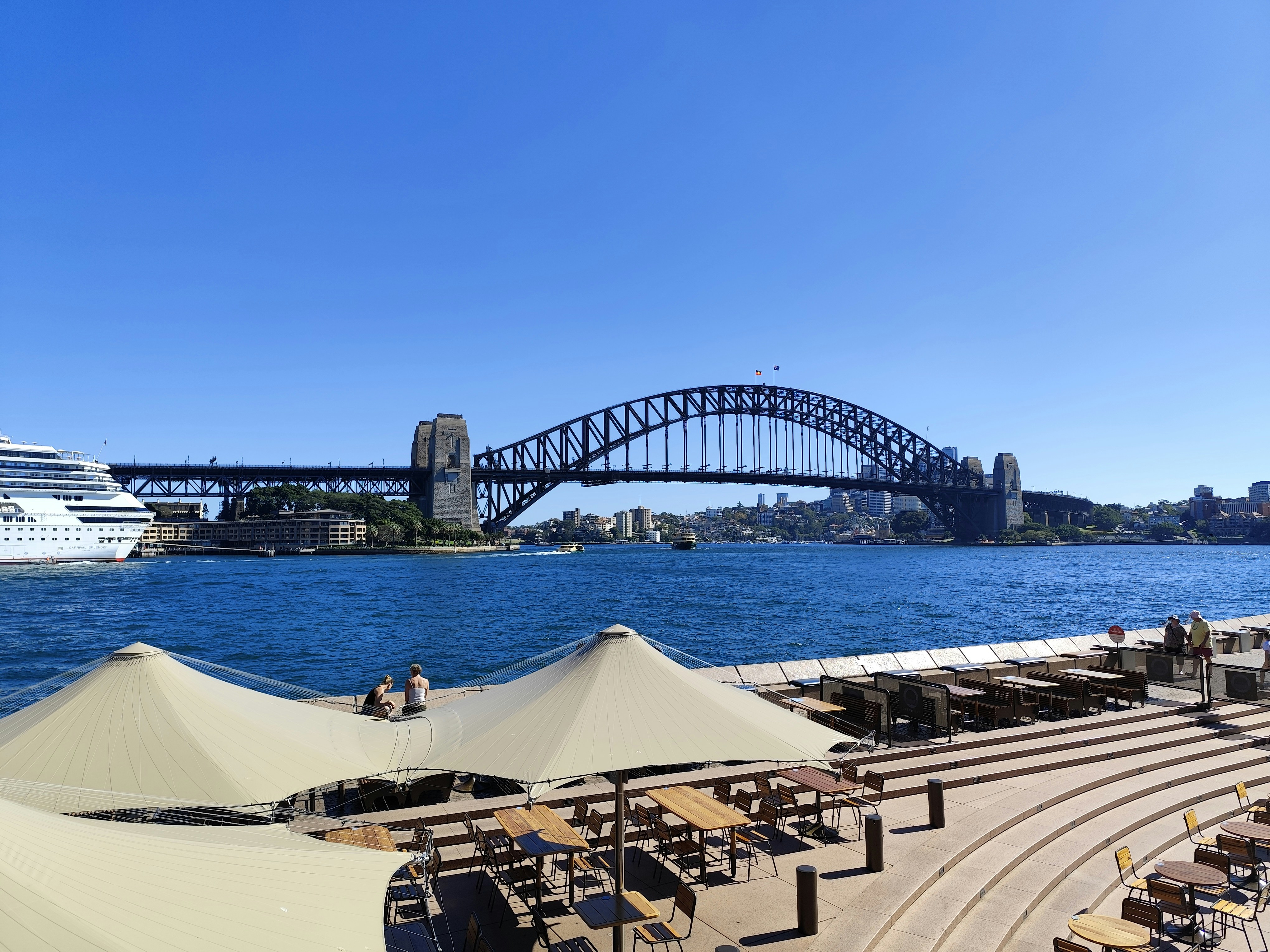 El puente de la bahía de Sídney domina un paisaje urbano soleado.