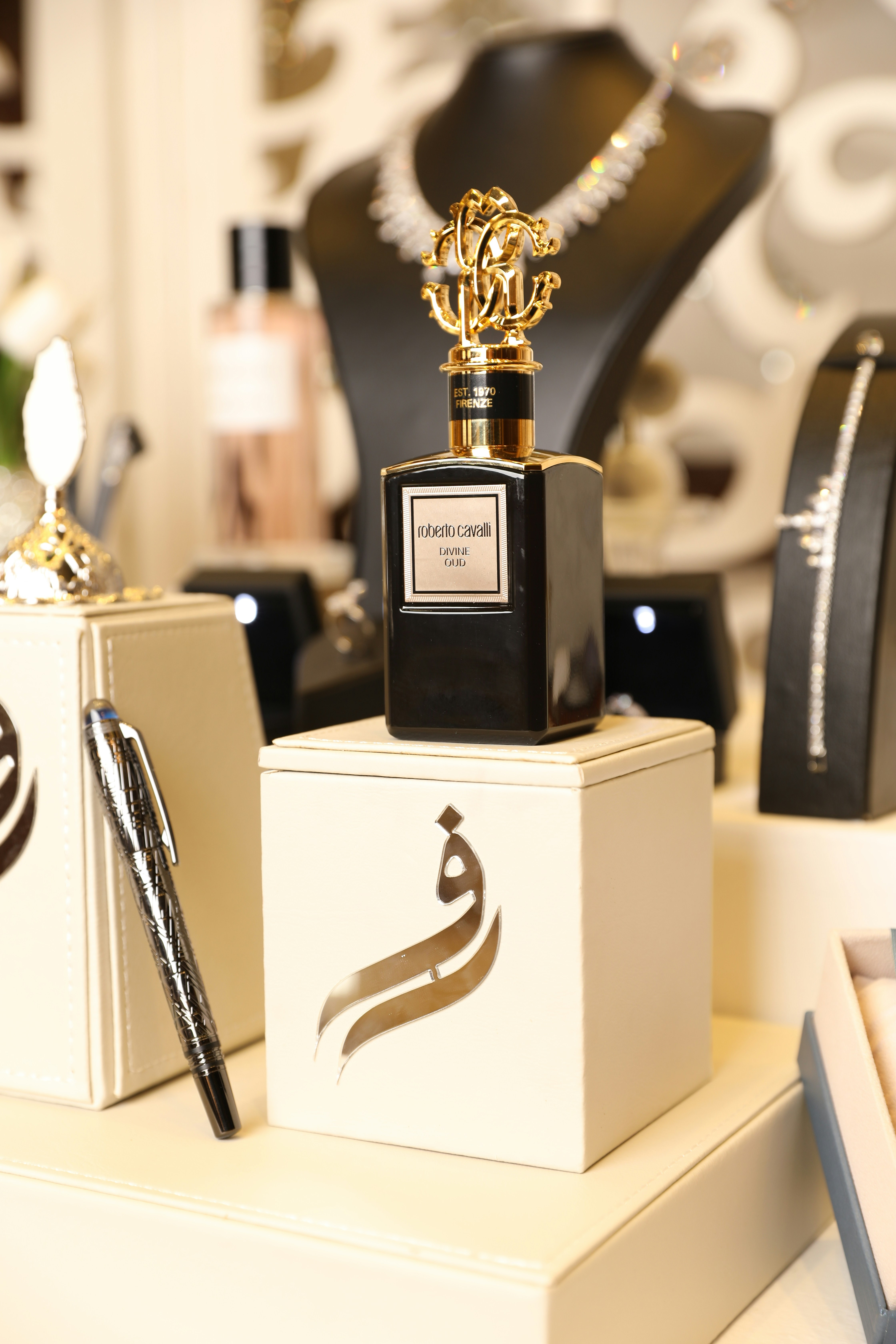 Perfume bottle on a white stand with jewelry.