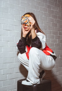 Woman with head covering squats in stylish outfit.