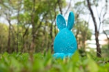 A blue easter bunny is in the green grass.