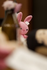 A crochet pink bunny peeks through the table.
