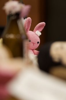A crochet pink bunny peeks through the table.