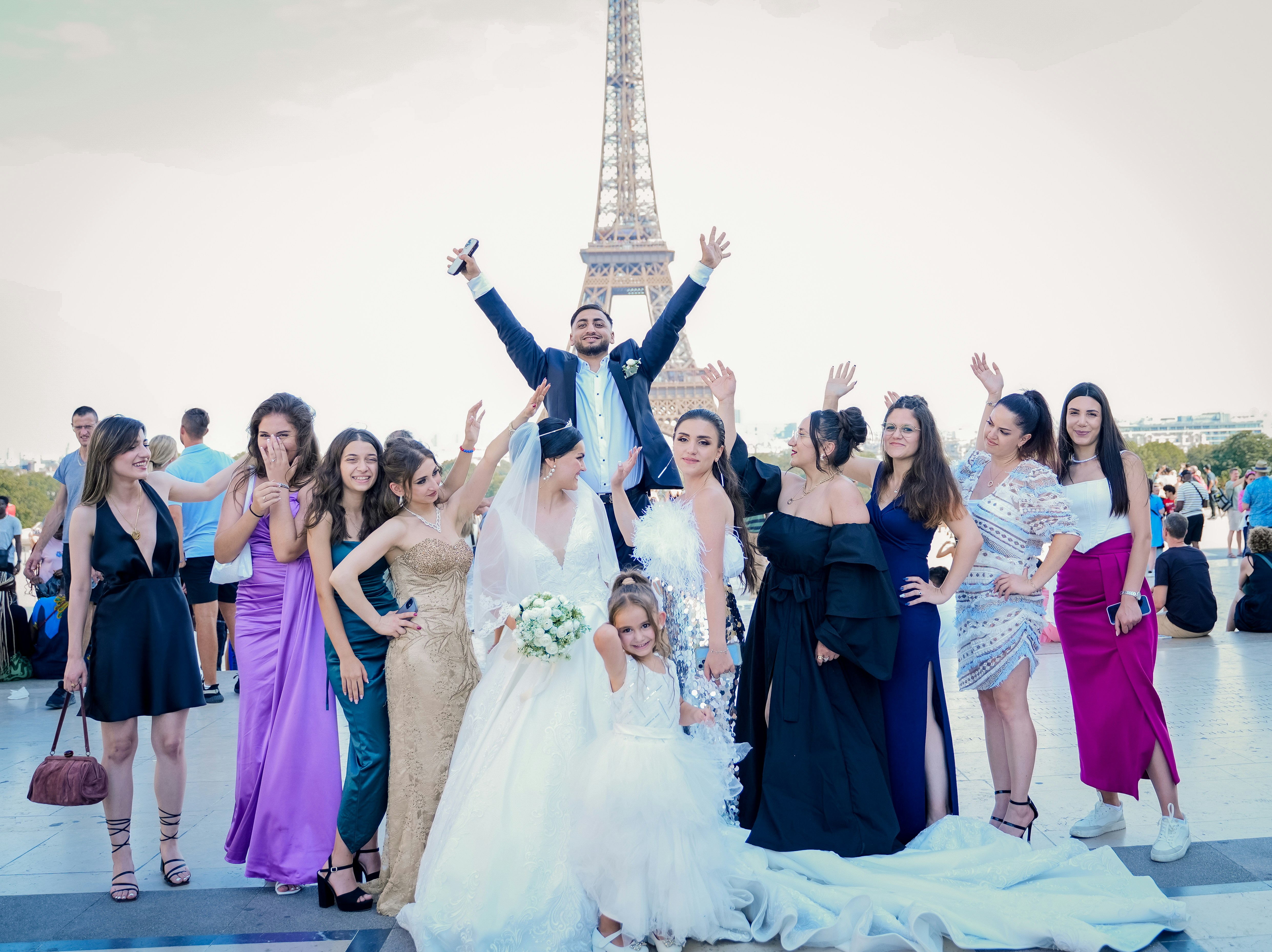 A wedding party celebrates in front of the eiffel tower.