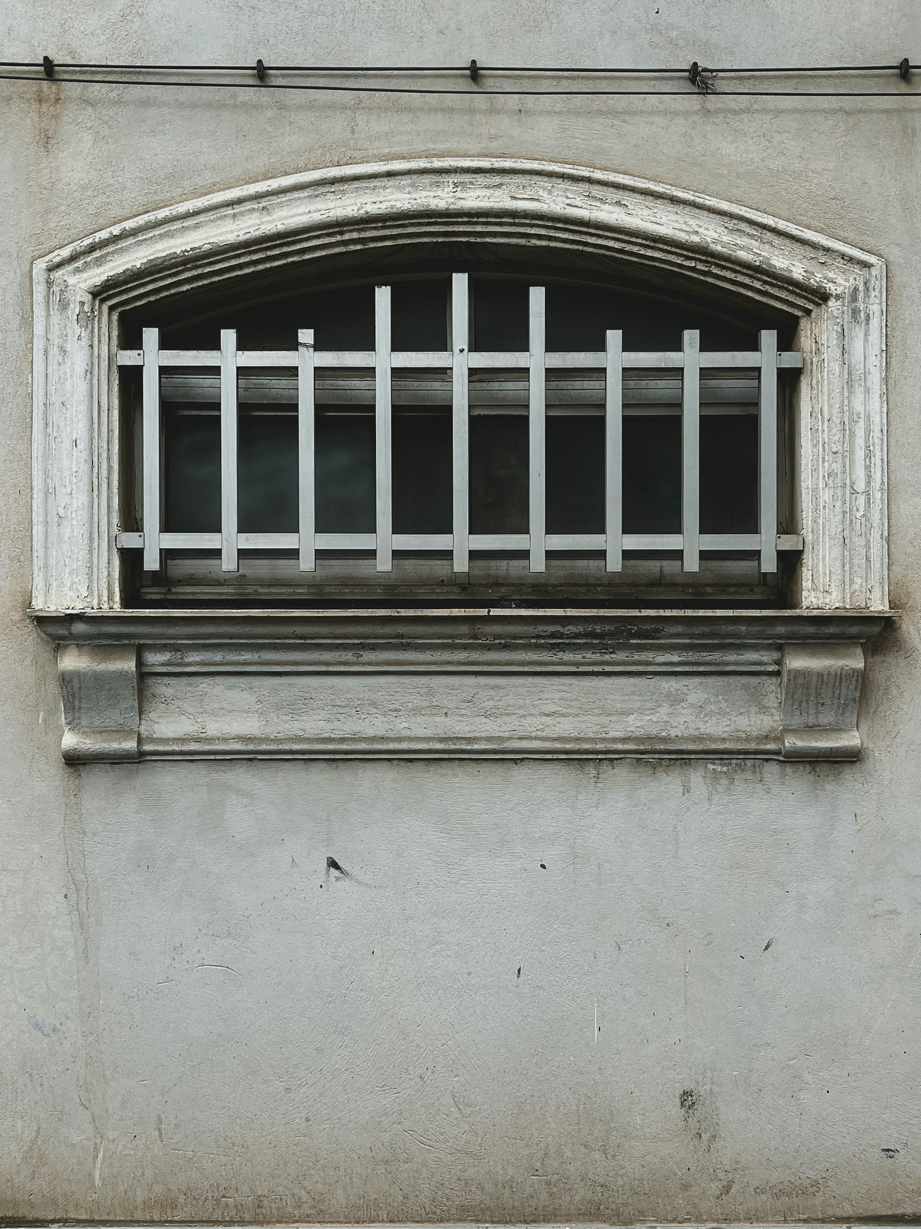 Window with bars in an old, gray wall.