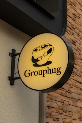 Grouphug cafe sign features an embracing coffee cup.