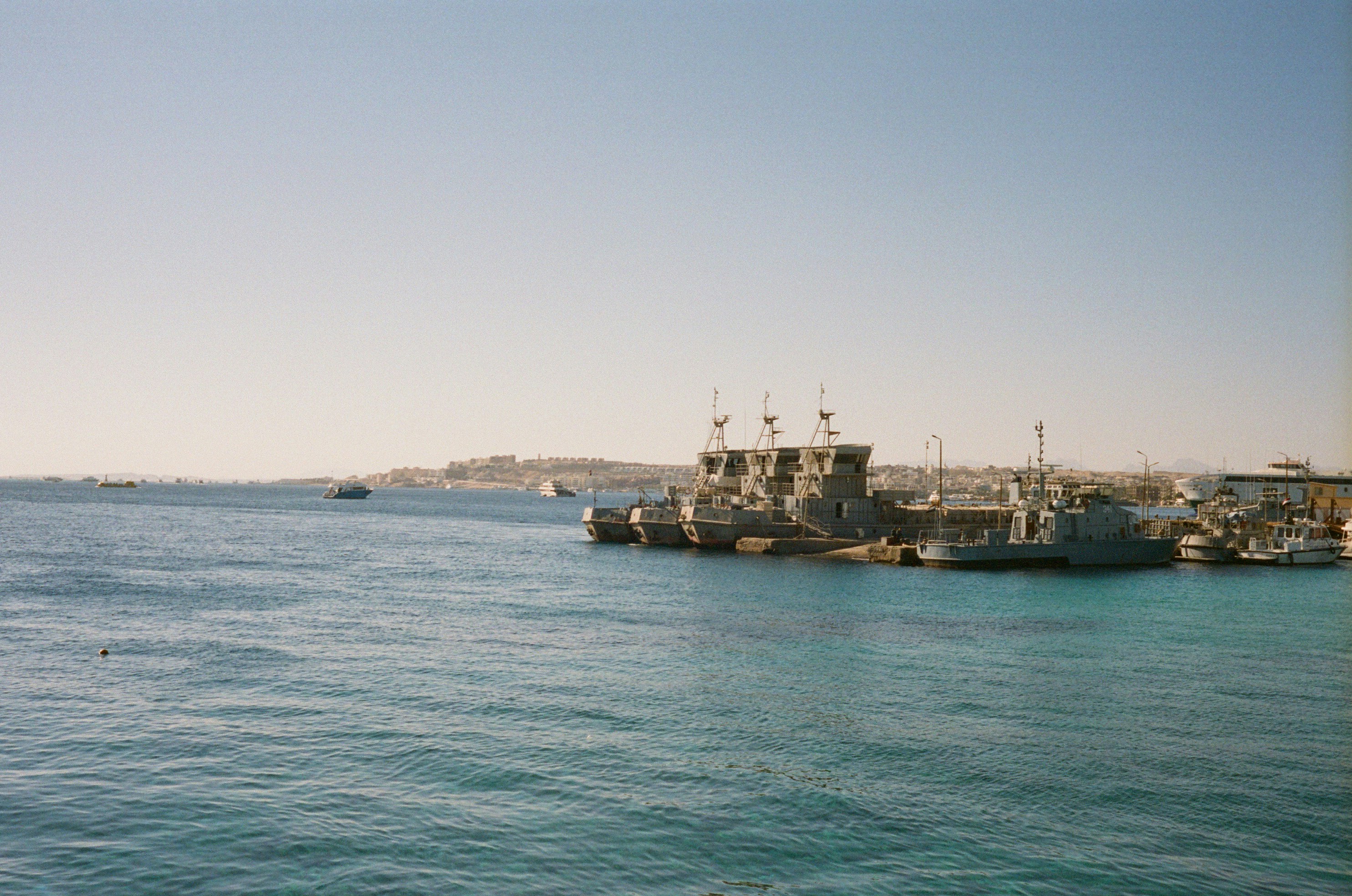 Ships moored beside turquoise water with coastal buildings in the distance in Hurghada