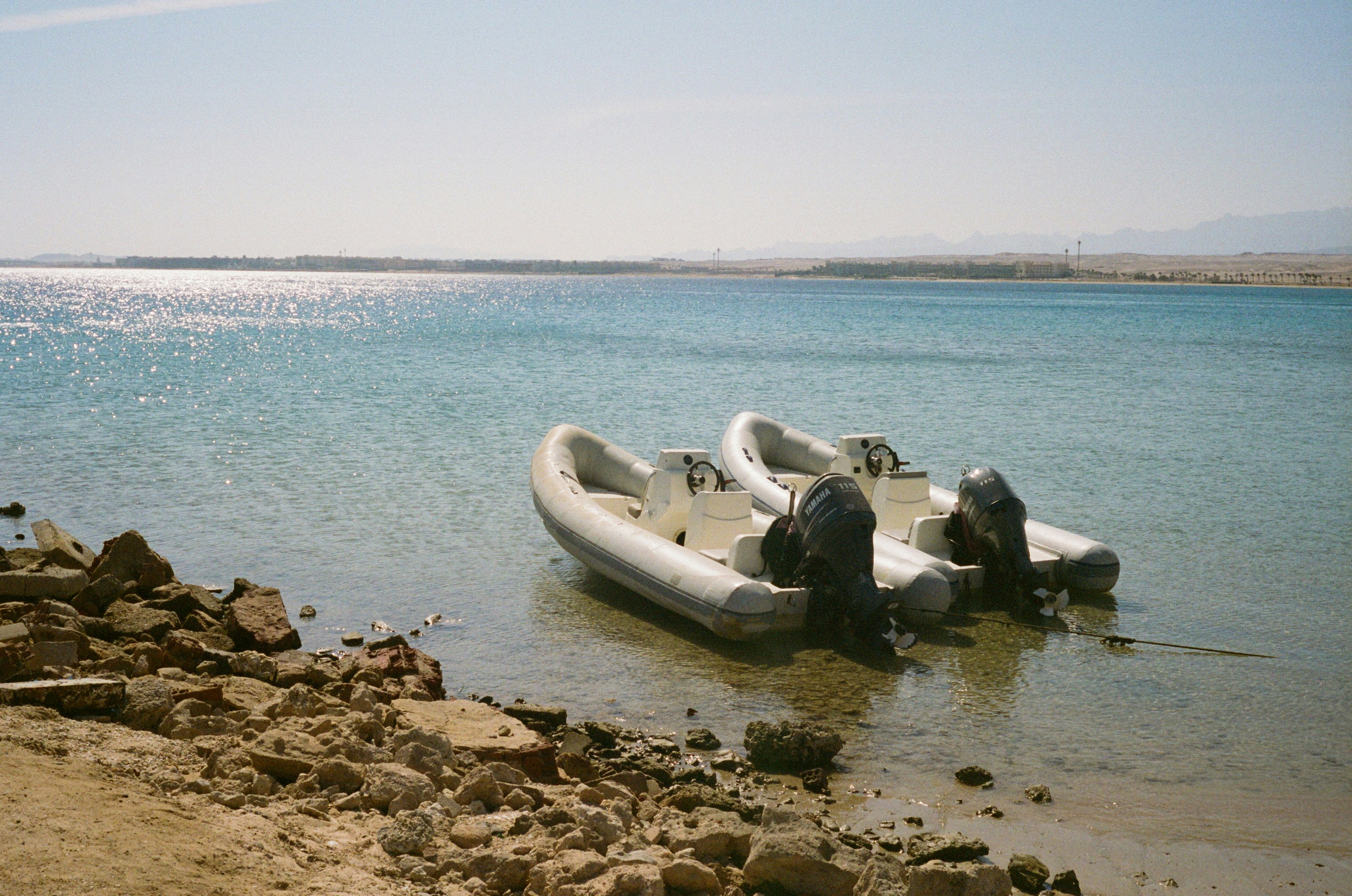 Two motorboats are moored near the water's edge.