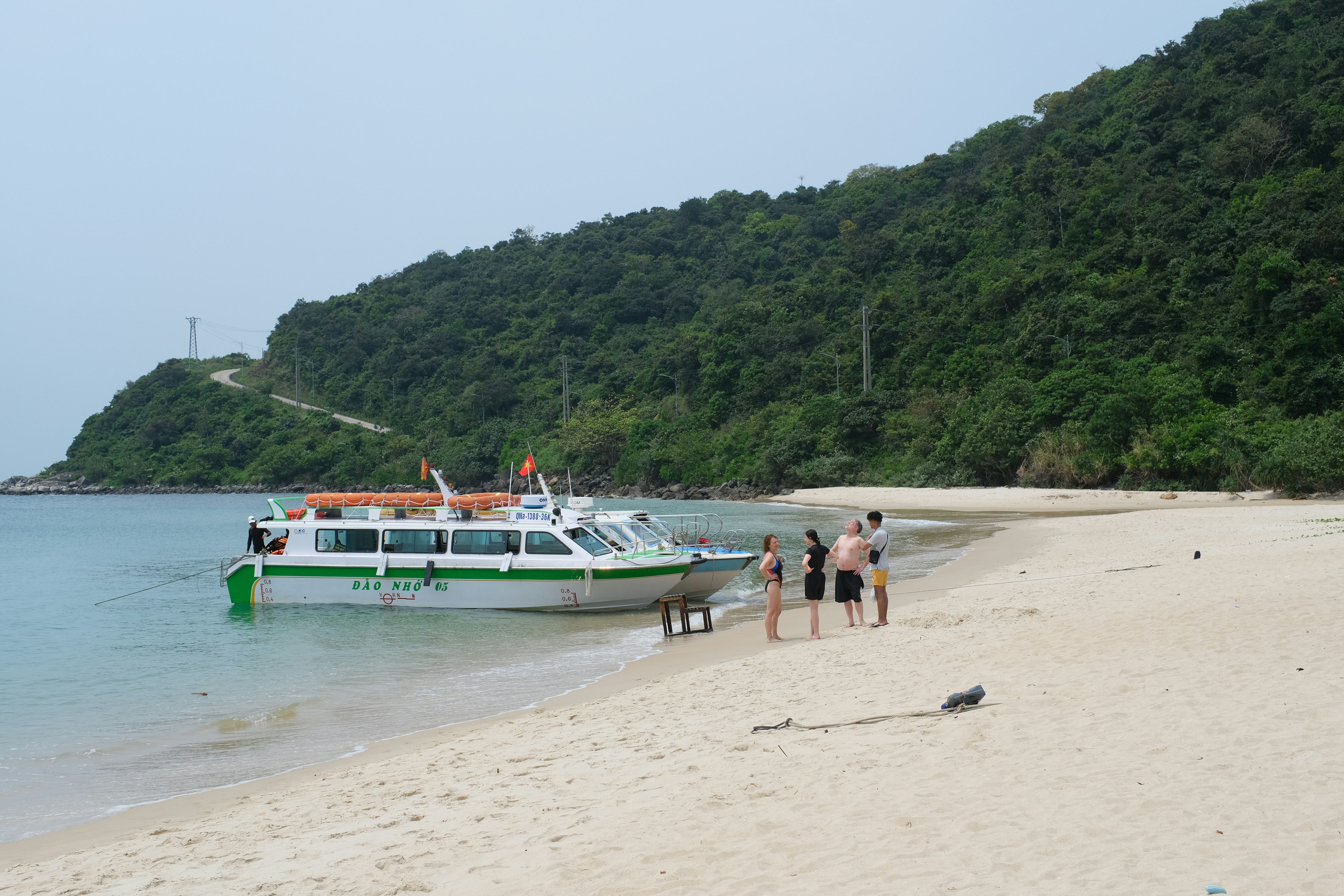 A boat and people are on a beautiful sandy beach.