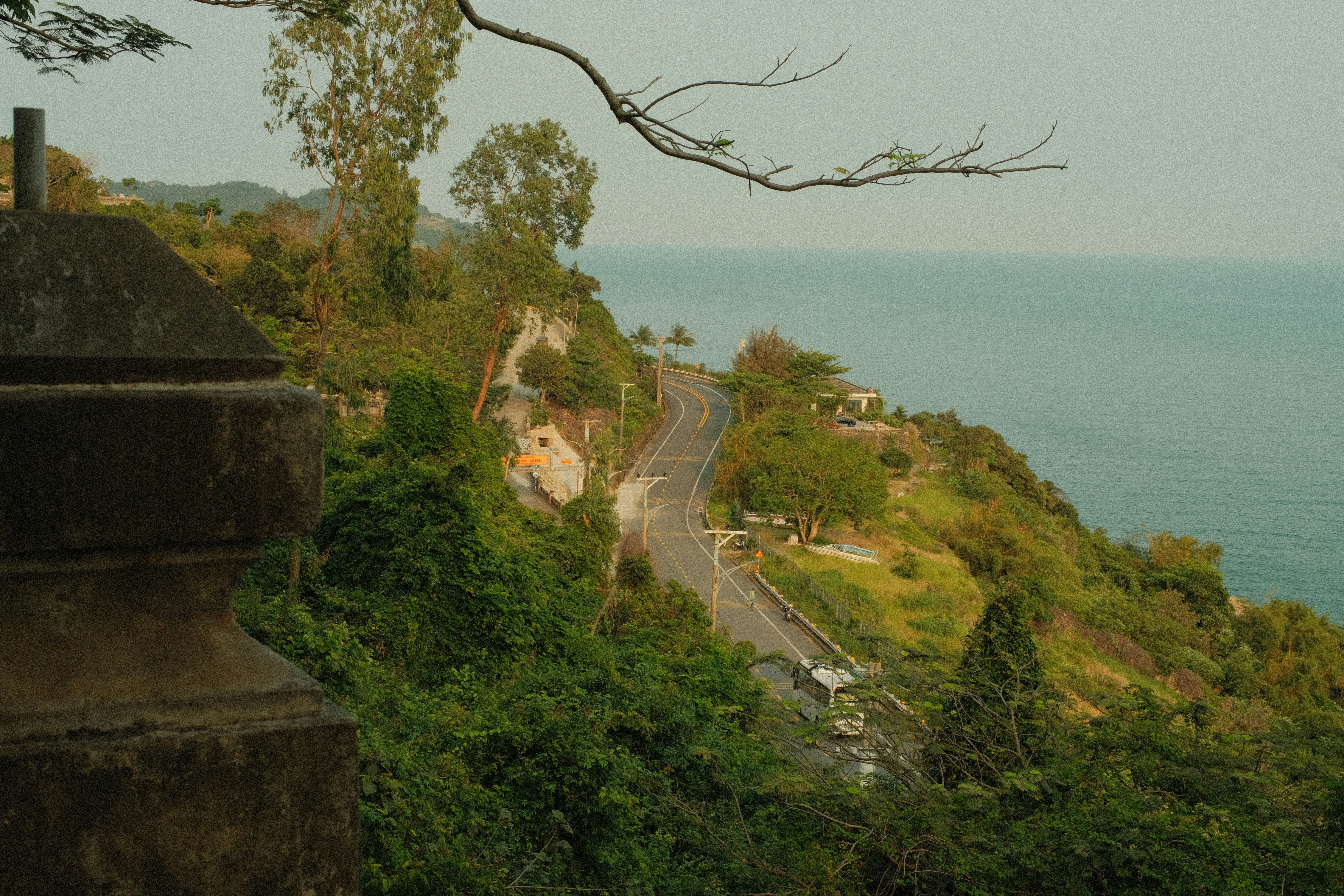 A coastal road curves along a hillside.