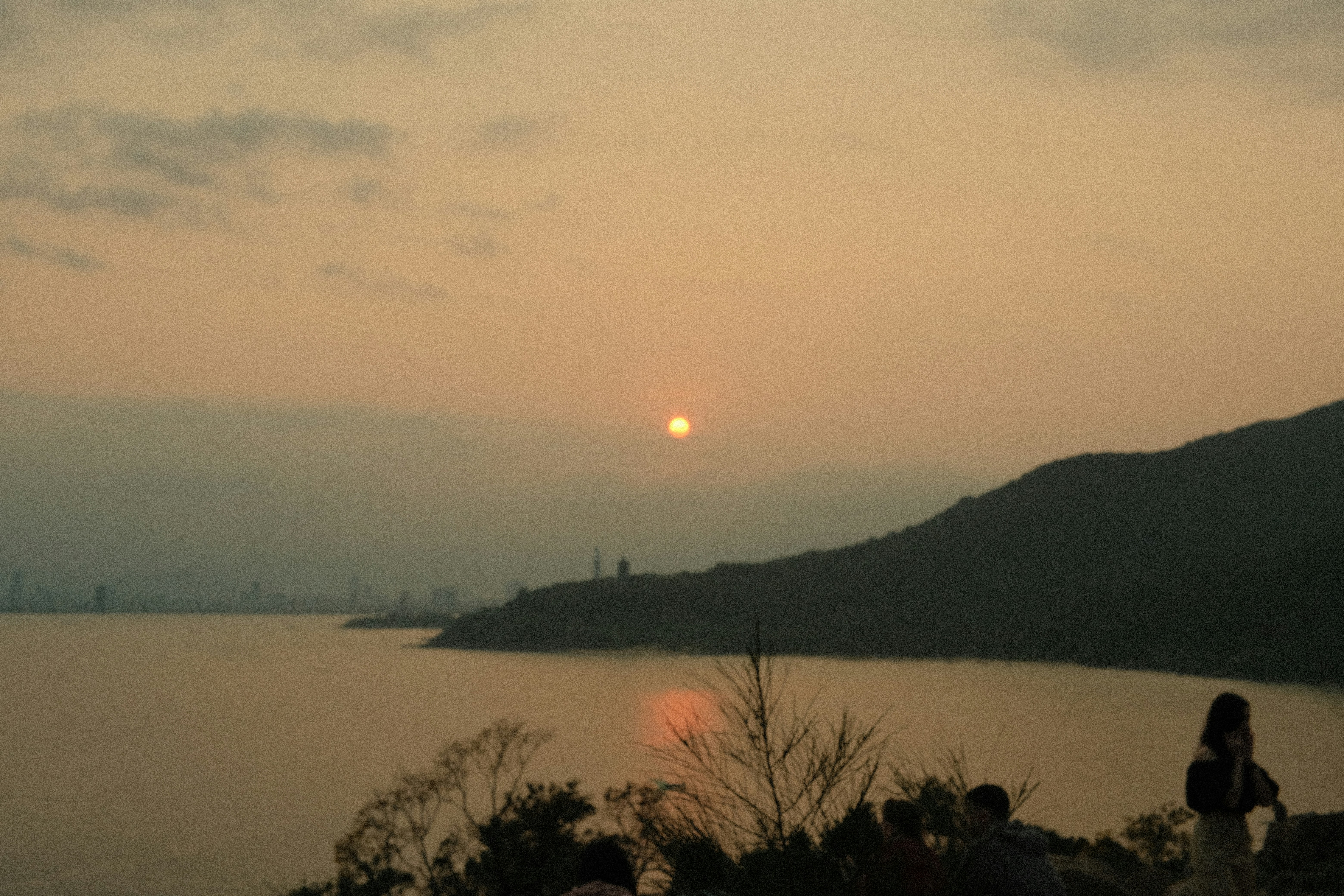 Sunset over a body of water with a mountain.