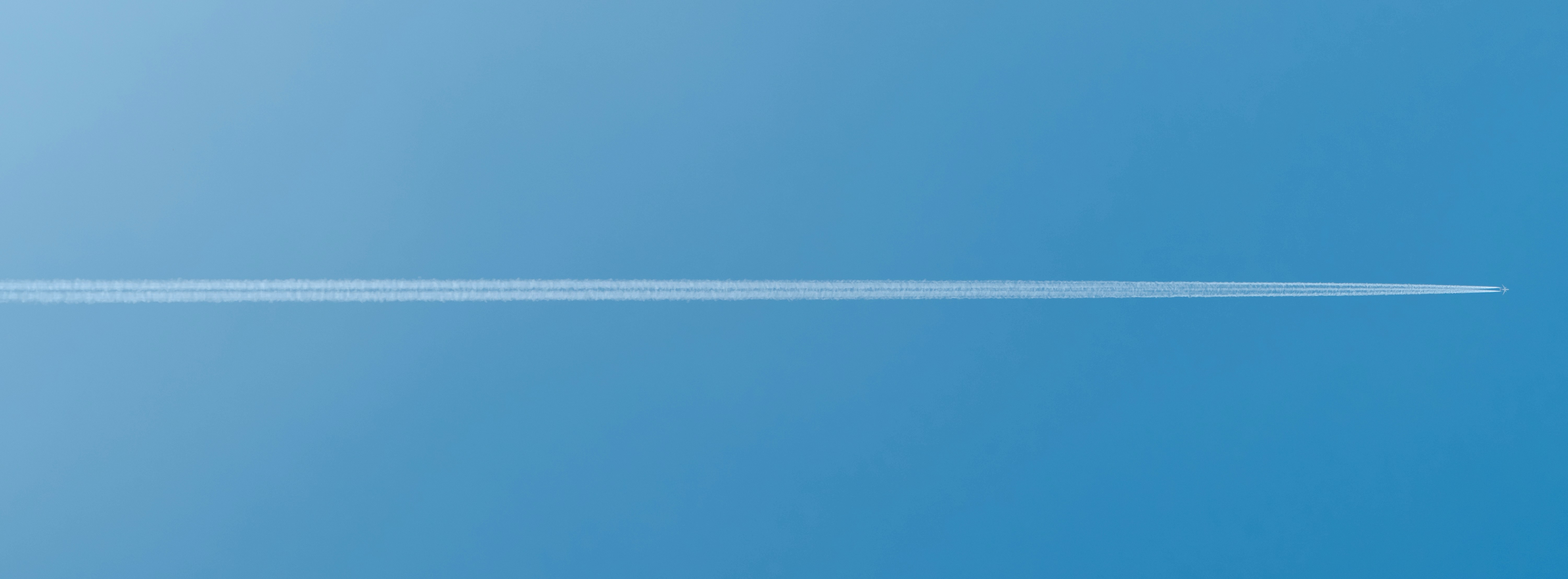 A jet contrail streaks across a blue sky. photo – Free Airplane Image ...