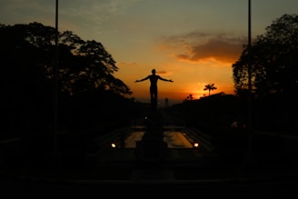 A statue silhouetted against a fiery sunset.