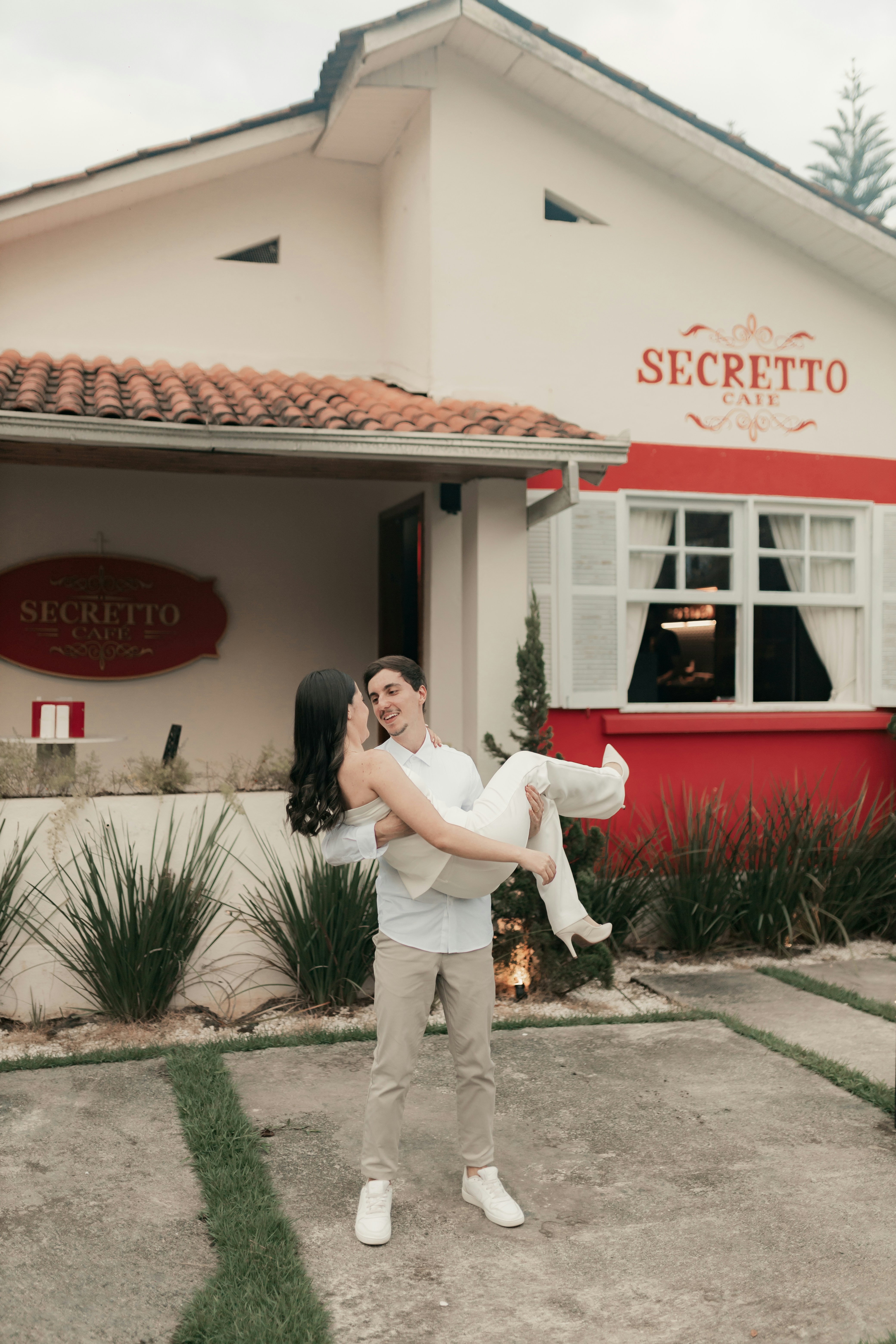 커플이 "secreto cafe"앞에서 포옹합니다.