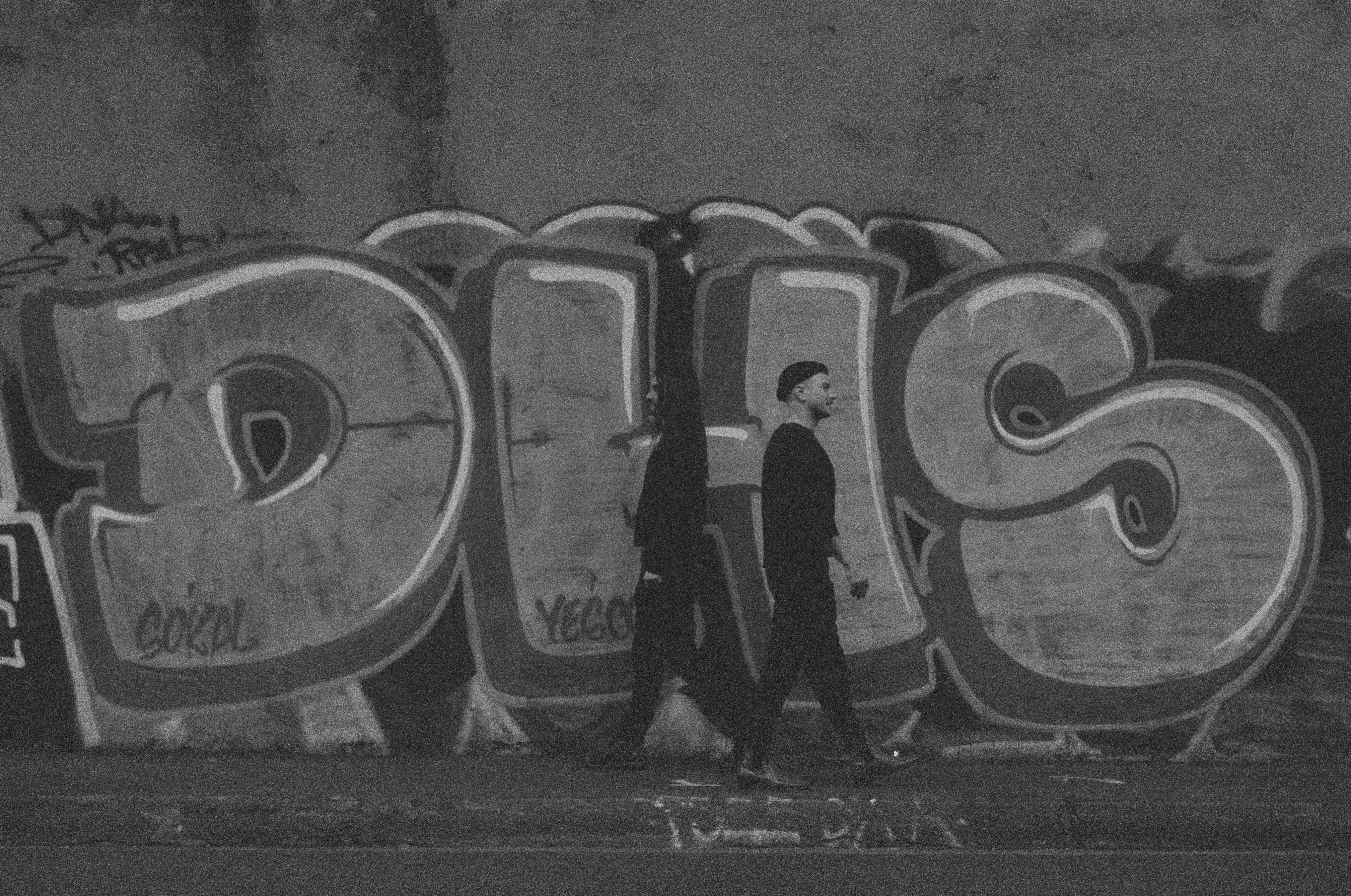Zwei Personen gehen an Graffiti vorbei.