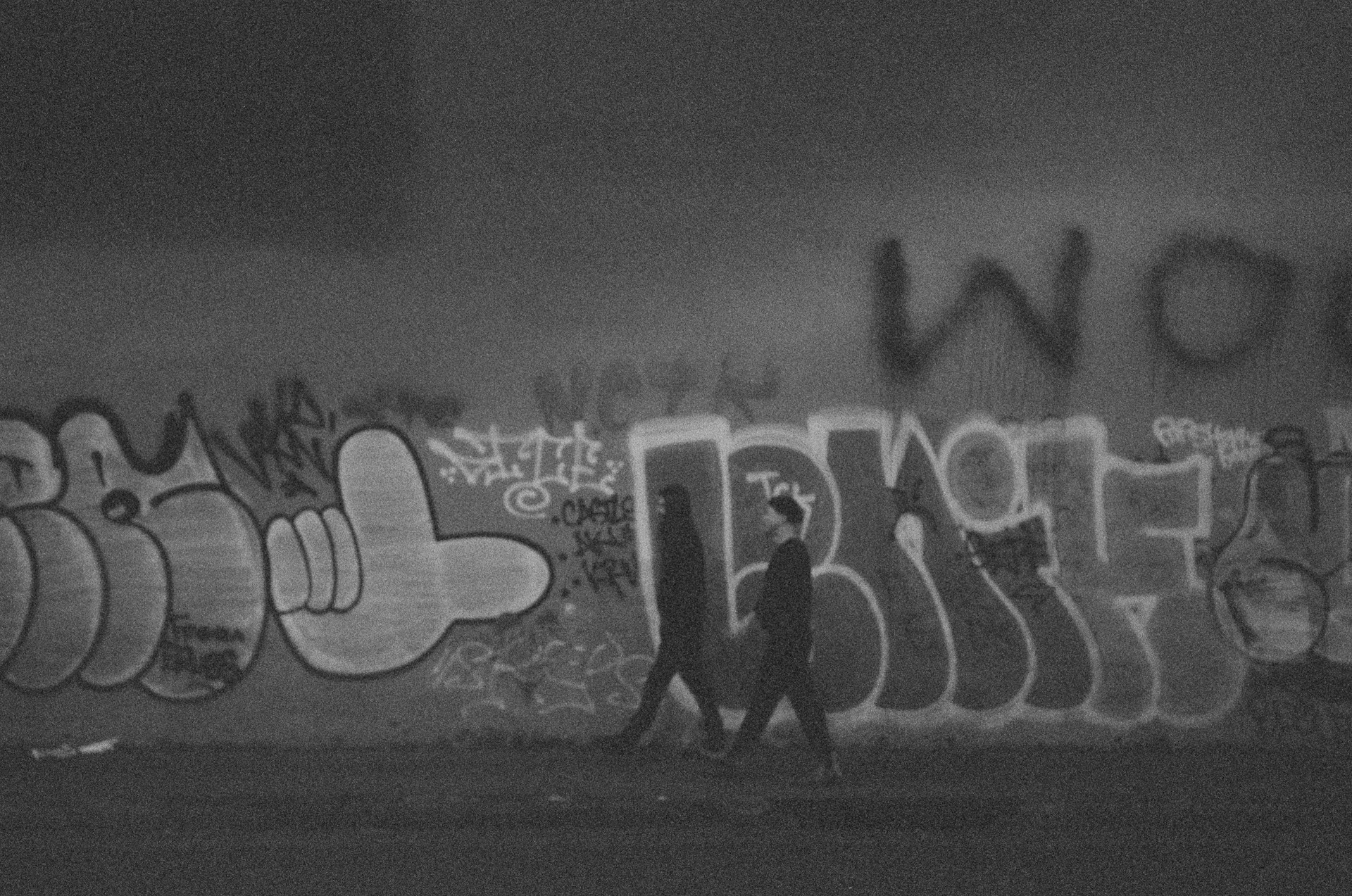 People walk past graffiti.