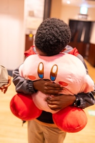 A person hugs a giant kirby plush.