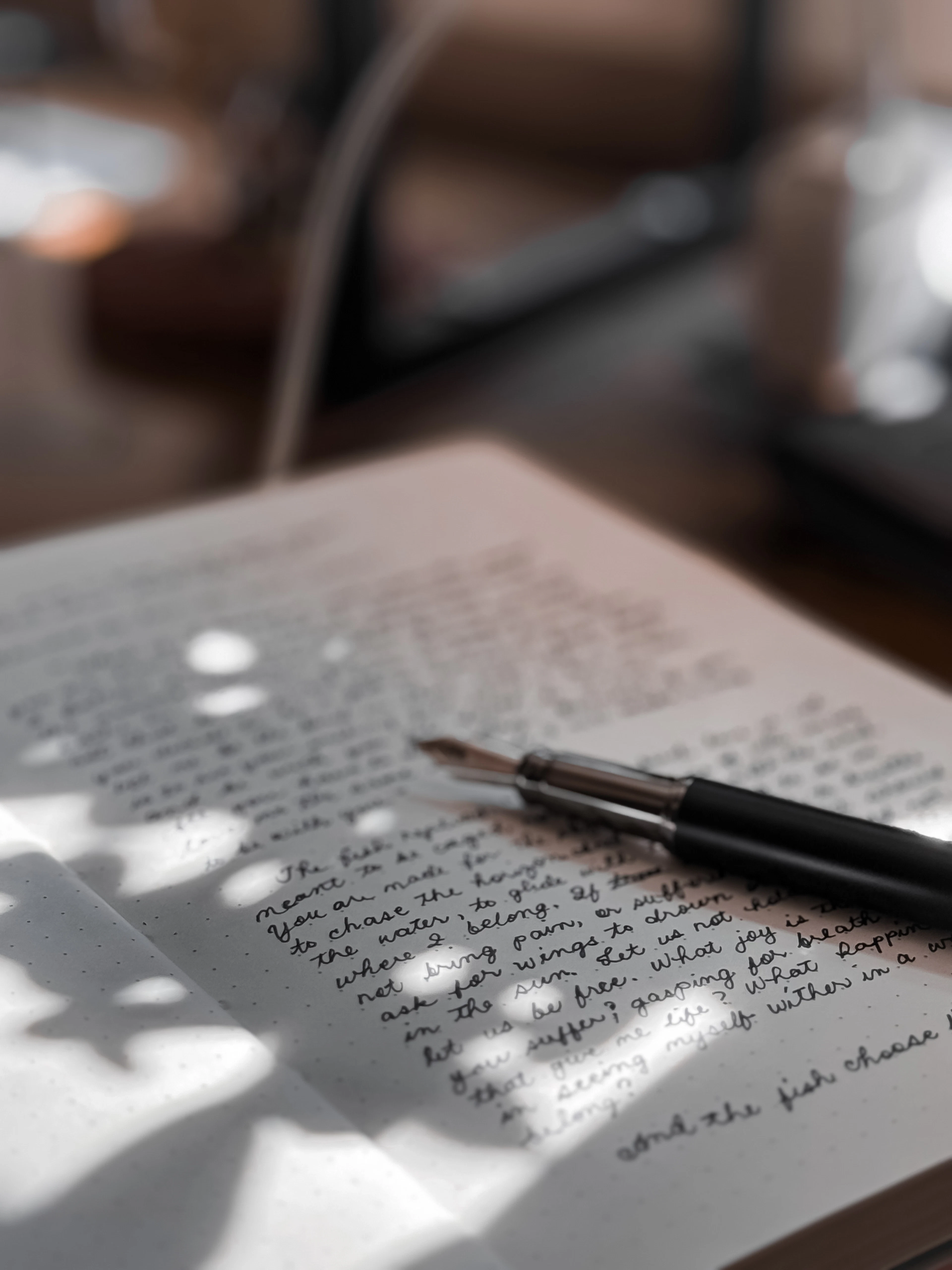 A handwritten poem in a notebook with a fountain pen resting across the page