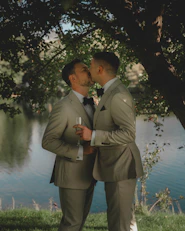 Two grooms share a kiss in a scenic setting