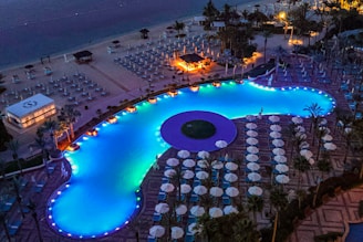 Lit pool and beach at night.