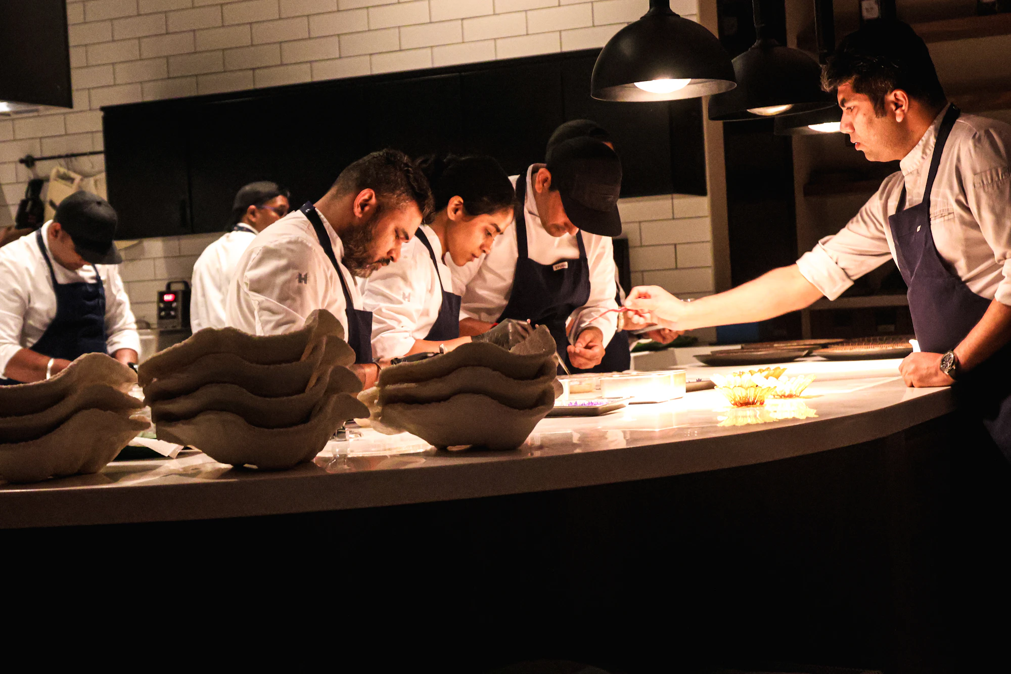 Chefs plating dishes together along the kitchen counter