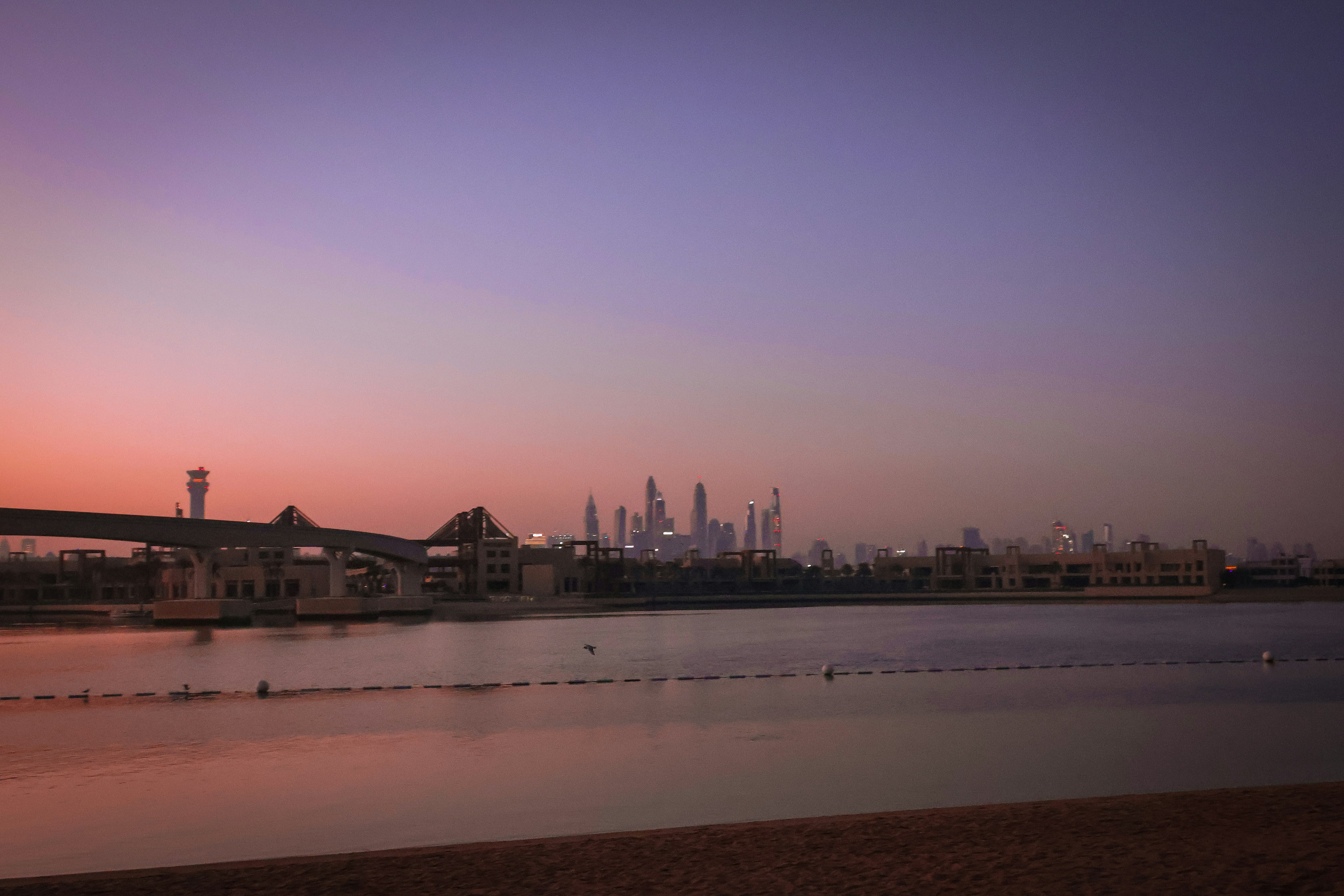 Sunset casts a pink glow over a city skyline.