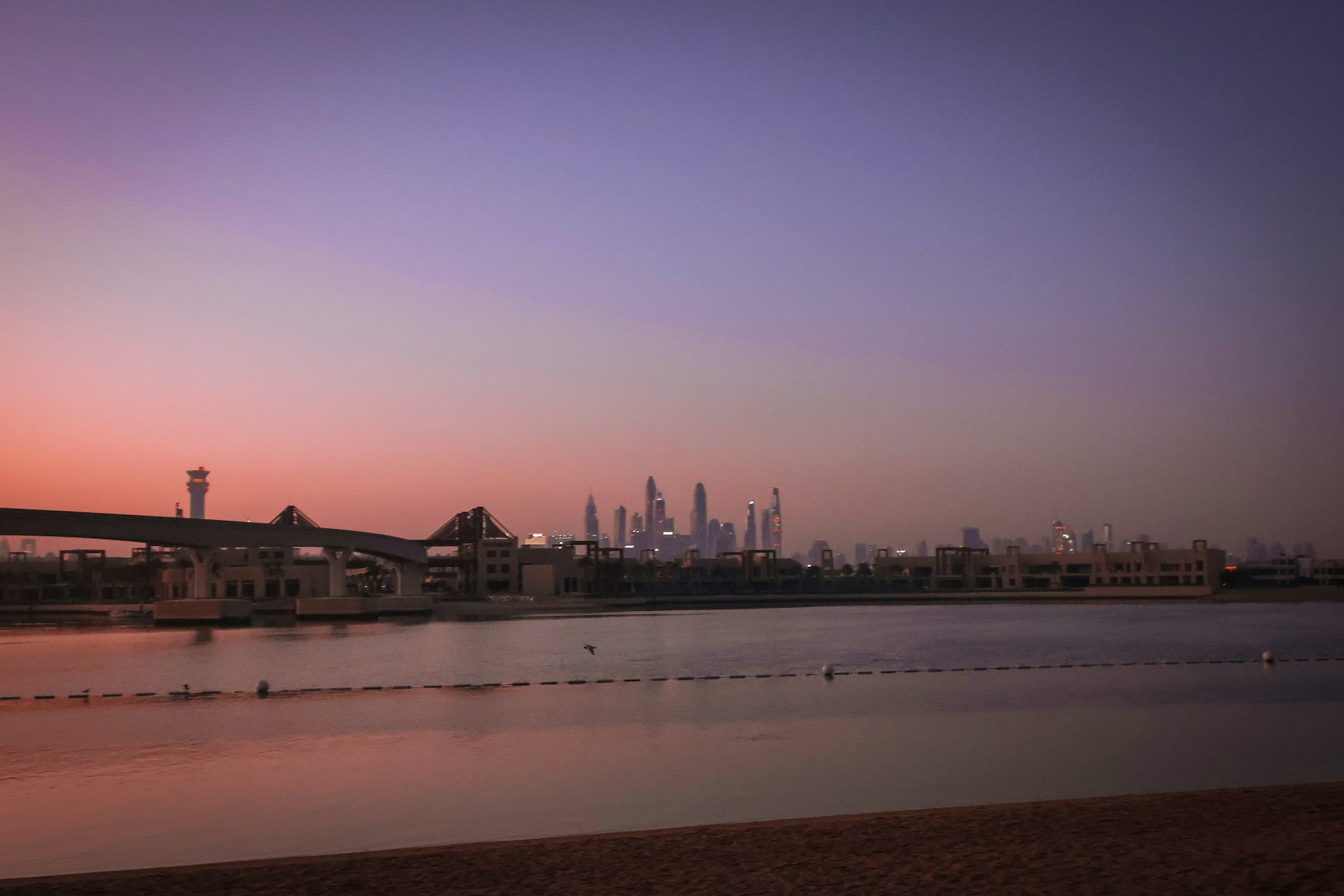 Sunset casts a pink glow over a city skyline.