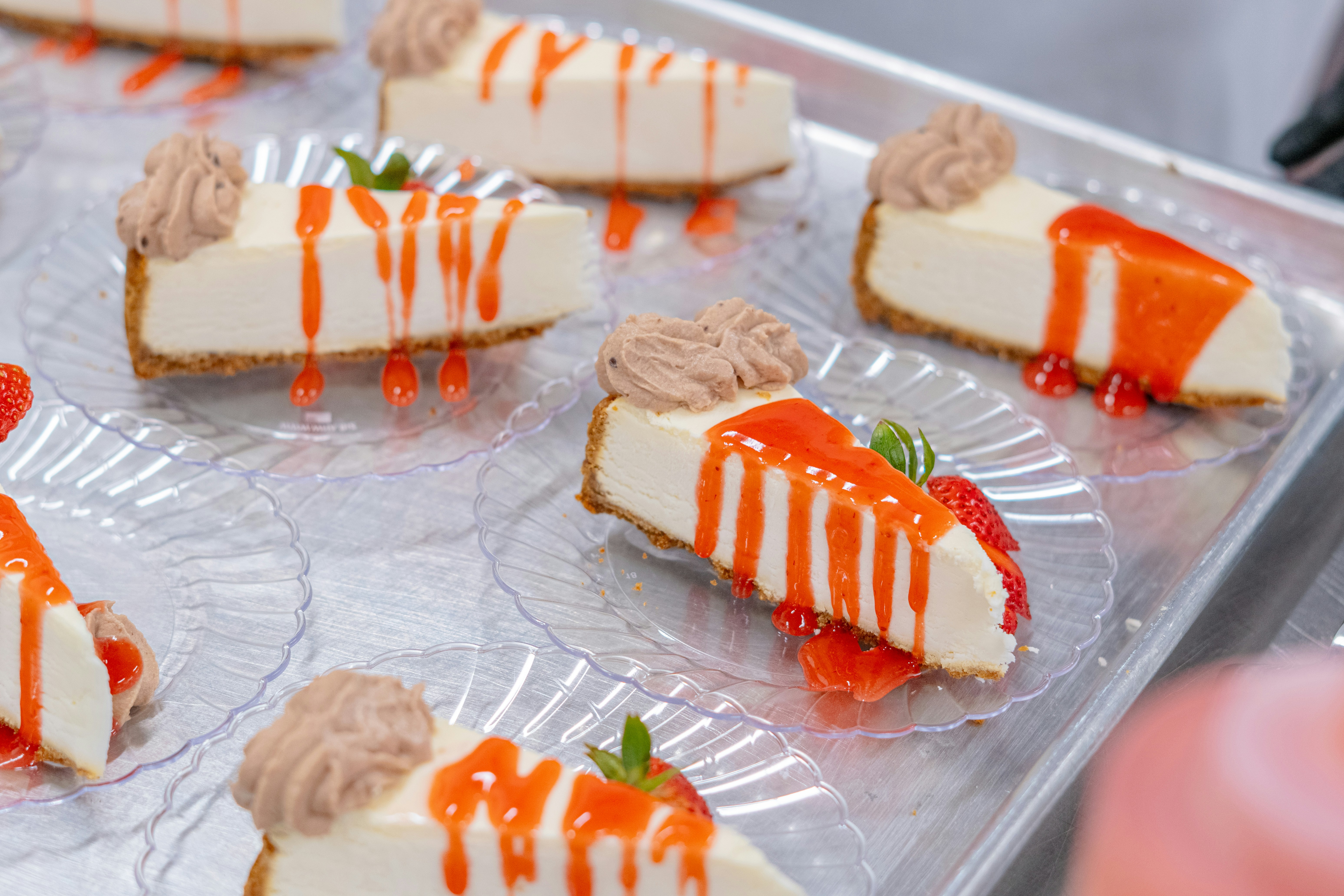 Cheesecakes are drizzled with red sauce and cream.