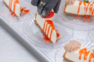 A chef adorns cheesecake slices with strawberries.