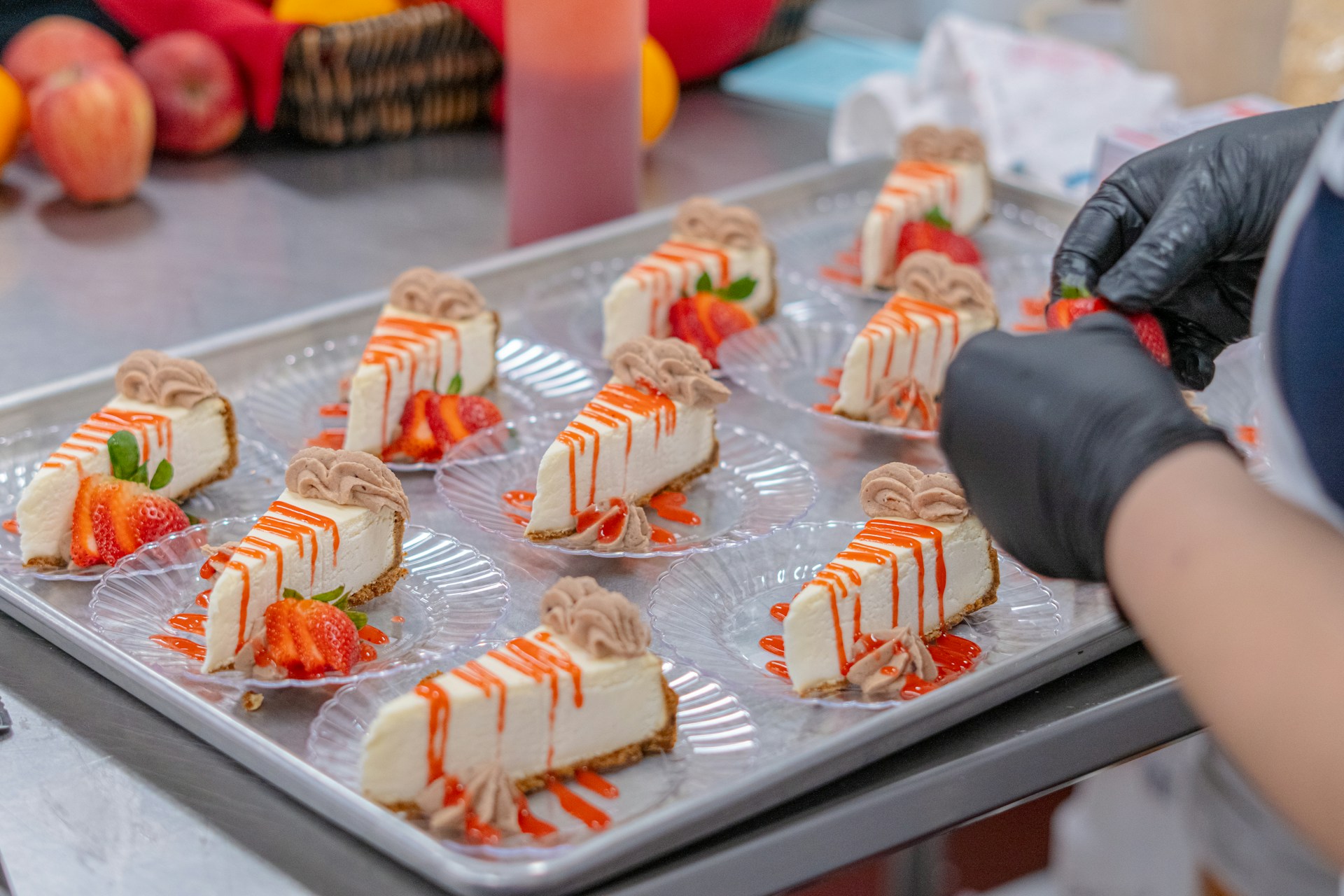 Chef garnishing cheesecake slices with strawberries.