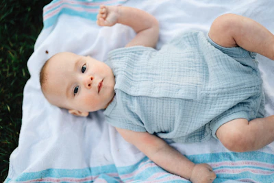 A baby is laying on a blanket looking up.