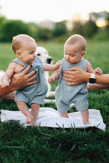 Twin babies are learning to walk with assistance.