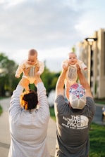 Parents lift their babies into the air.