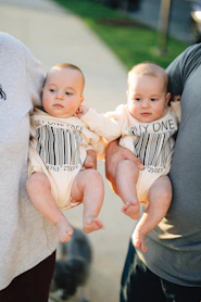Parents are holding two adorable twin babies.