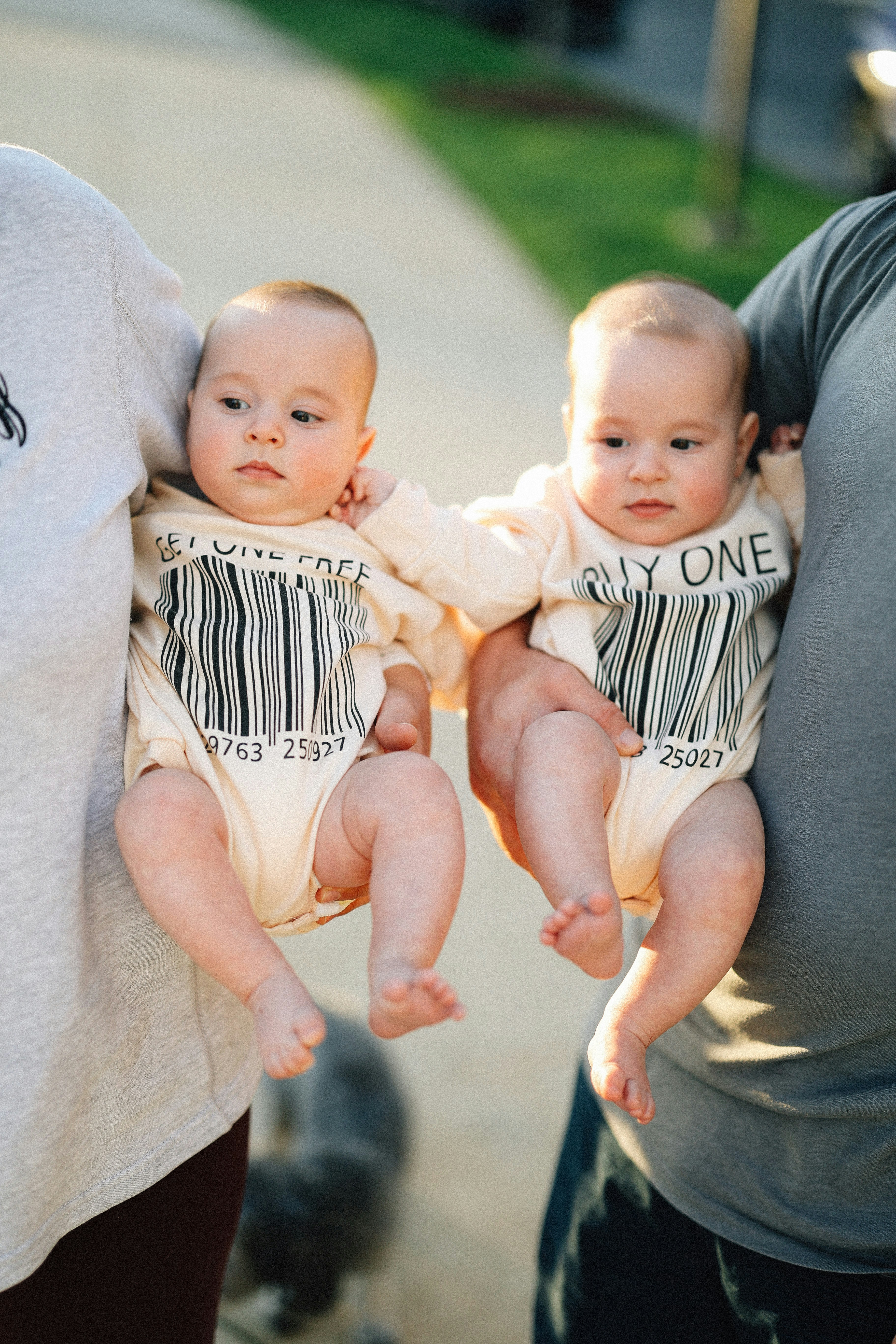 Parents are holding two adorable twin babies.