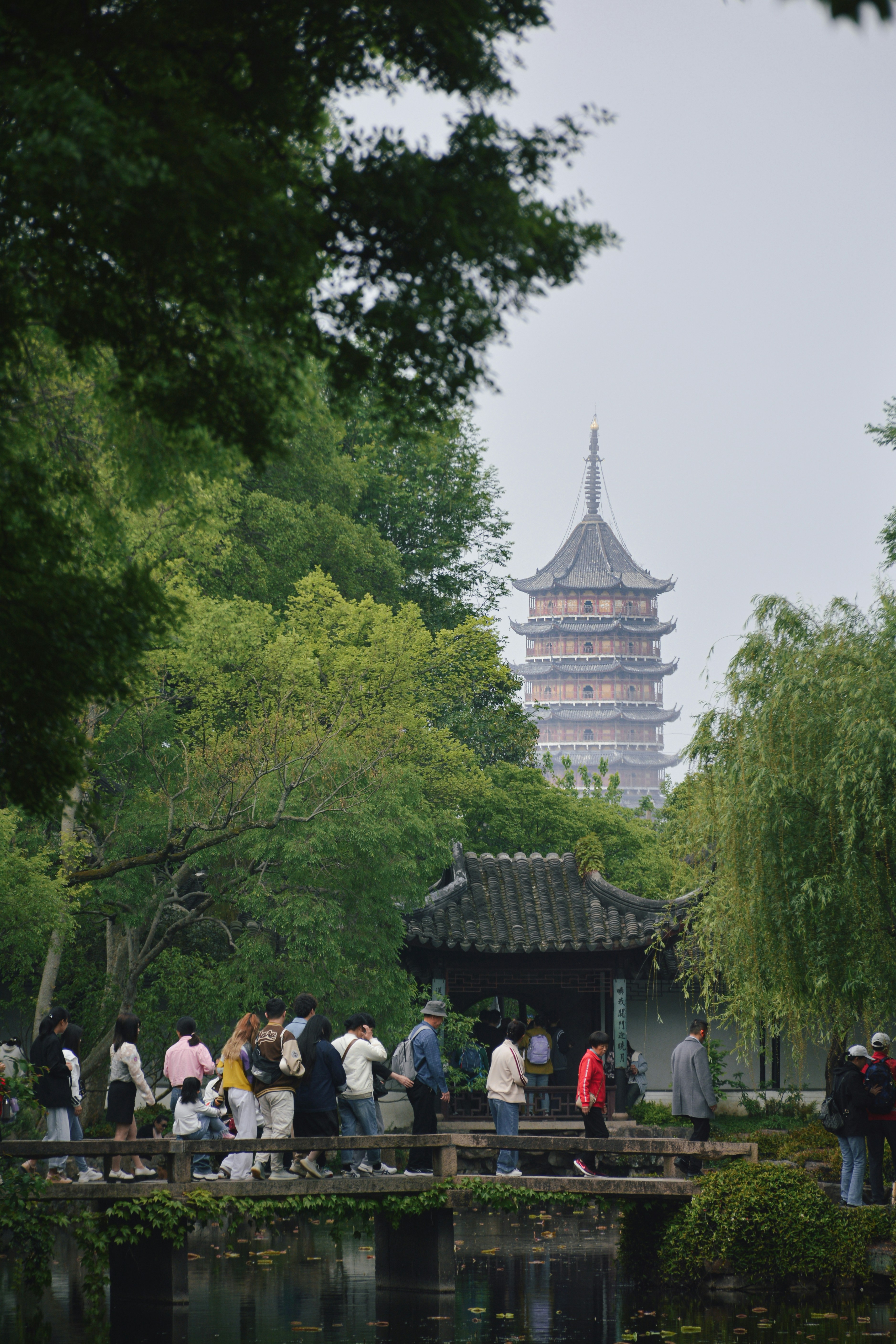 Menschen laufen auf einer Brücke, im Hintergrund eine Pagode.