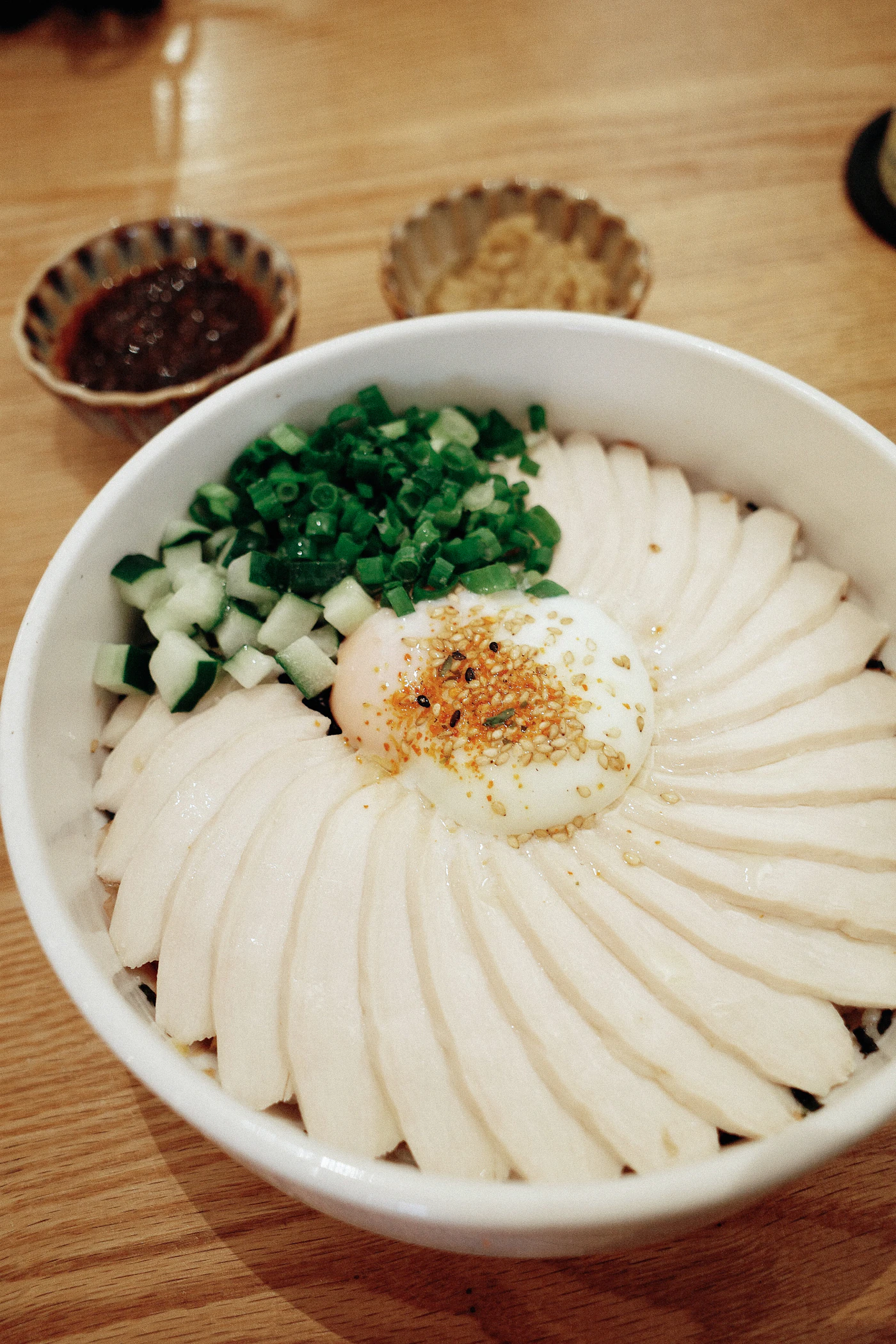 Sliced sesame chicken rice bowl with cucumber and egg