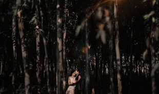 A woman stands alone in the forest.