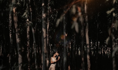 A woman stands alone in the forest.