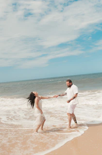 Couple dances joyfully in the ocean's shallow water.