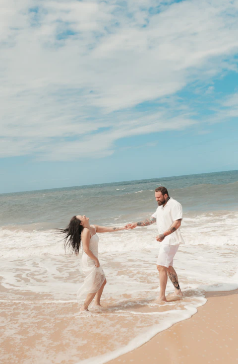 Couple dances joyfully in the ocean's shallow water.