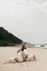 Couple sitting back-to-back on the beach.